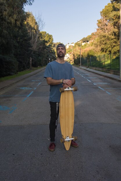Man practicing with his long board on a lonely street in a sunset
