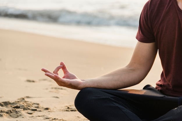 Uomo che praticano yoga sulla spiaggia