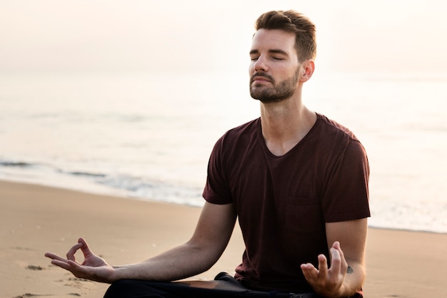 Uomo che praticano yoga sulla spiaggia