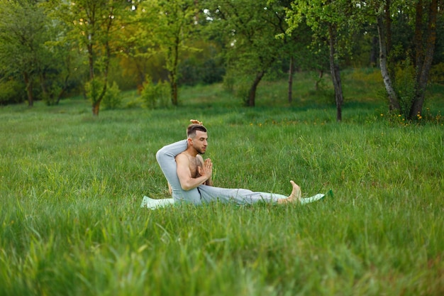 Man practicing yoga in the grass outdoors