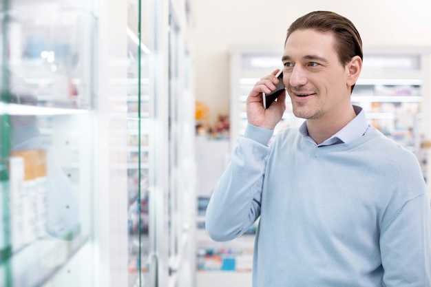 Man praten aan de telefoon in een drogisterij