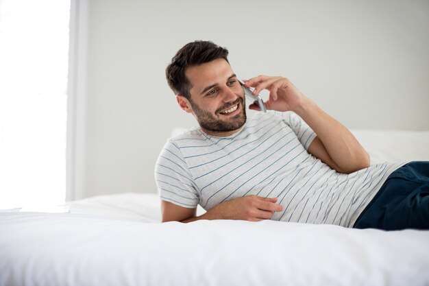 Man praten op mobiele telefoon in de slaapkamer thuis