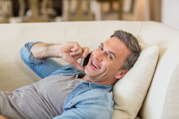 Man praten op mobiele telefoon in de woonkamer