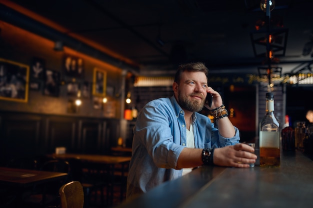 Man praten via mobiele telefoon aan de balie in bar