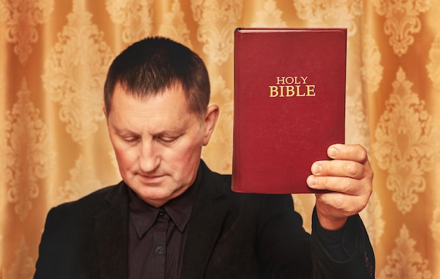 Молящийся мужчина с опущенной головой и Библией в руке