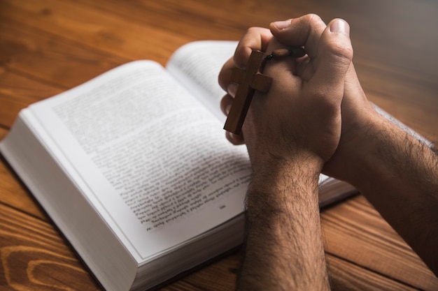 a man praying on a book on a dark surface