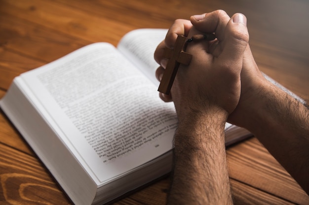 A man praying on a book on a dark surface