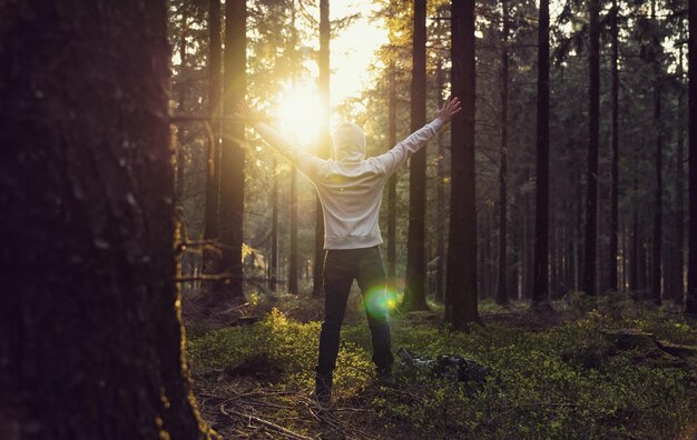 Man praying at sunset in the deep woods raised hands