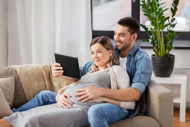 man and pregnant woman with tablet pc at home