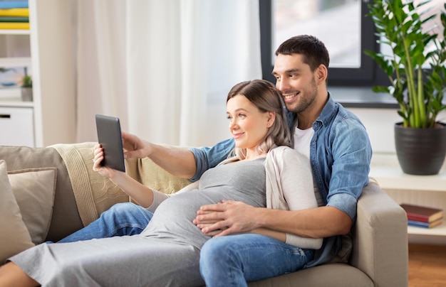 man and pregnant woman with tablet pc at home