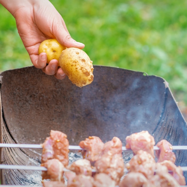 男はジャガイモでバーベキュー肉を準備します