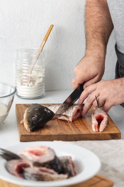 男は家庭の台所でcar川の魚を準備します。健康食品とダイエット食品の調理