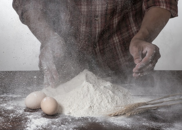 Man preparing bread dough on wooden table in a bakery close up