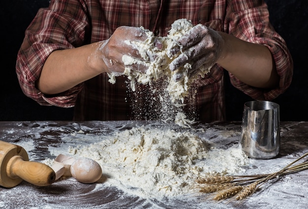 Man preparing bread dough on wooden table in a bakery close up