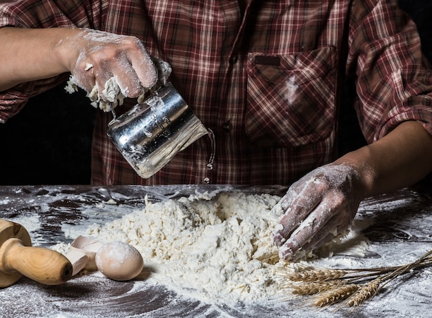 Man preparing bread dough on wooden table in a bakery close up