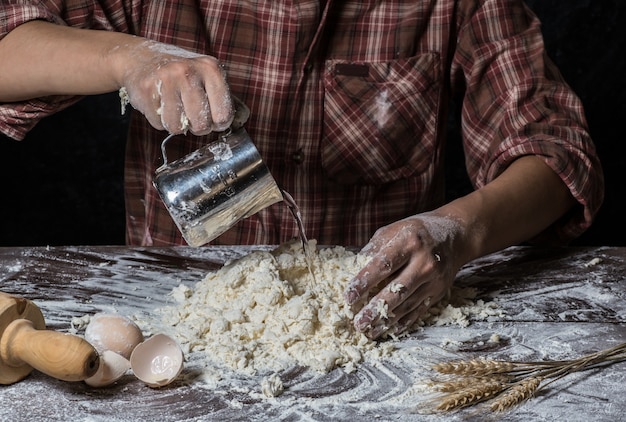 Man preparing bread dough on wooden table in a bakery close up