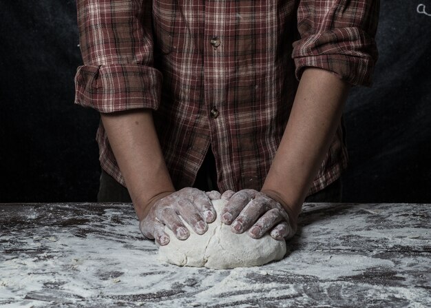 Photo man preparing bread dough on wooden table in a bakery close up