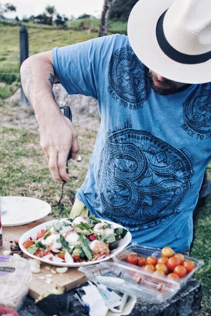 Foto uomo che prepara il cibo al tavolo nel cortile