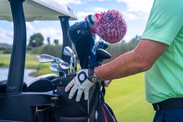 Man preparing the golf clubs in the buggy man playing golf