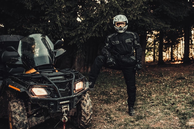 Man preparing his quad for extreme ride in forest