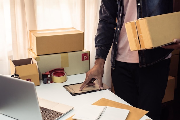 Man preparing a parcel for delivery at online selling business\
office ecommerce drop shipping