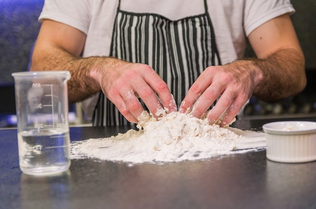 Uomo che prepara la pasta della pizza sulla tavola di granito nero