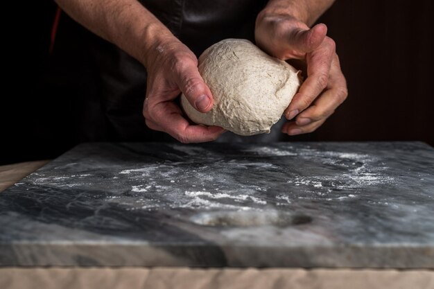 Man preparing pizza dough on marble table