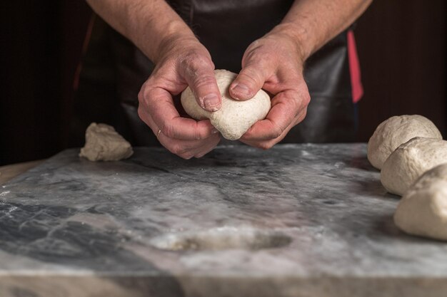 Man preparing pizza dough on marble table