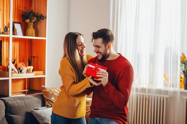 Man presenting gift to his girlfriend in room at home Symbol of their love Man looks tenderly at his