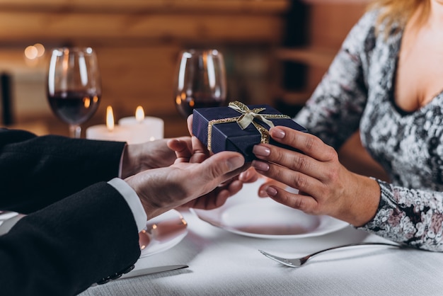 A man presents a gift to a woman at dinner