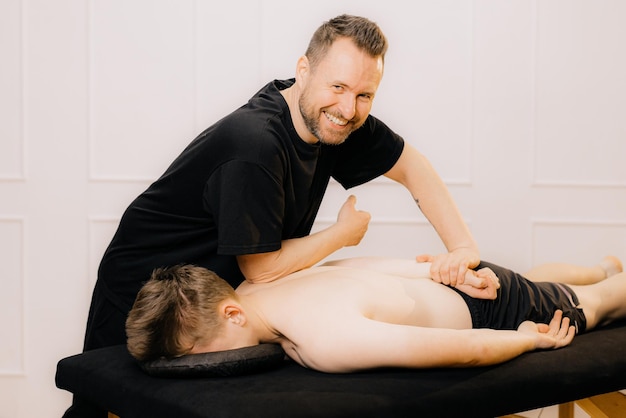 Мужчина, профессиональный врач-остеопат, фиксирующий и растягивающий спину человека руками во время тренировки