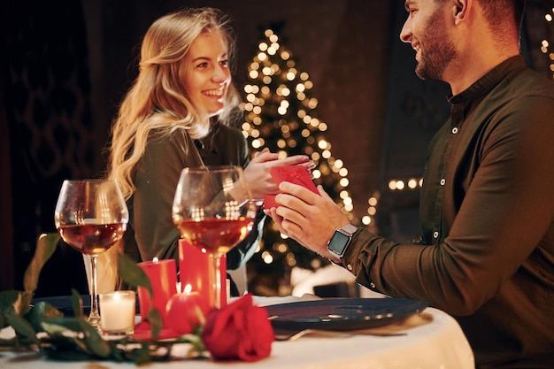 Man proposing a beautiful woman to marry him in an elegant\
restaurant young lovely couple have romantic dinner indoors\
together