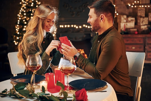 Man proposing a beautiful woman to marry him in an elegant\
restaurant young lovely couple have romantic dinner indoors\
together