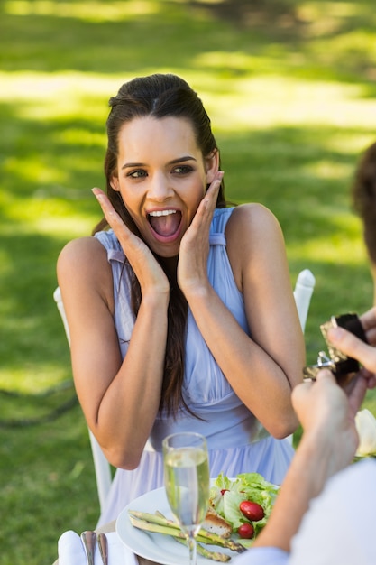 Man proposing shocked woman at an outdoor cafã©