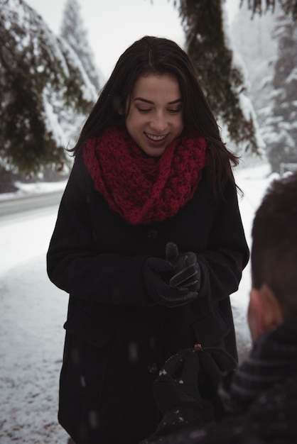 Man proposing to woman with ring in forest during winter