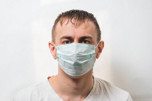 Uomo in maschera protettiva. medico in maschera chirurgica sul muro bianco. protezione dai germi