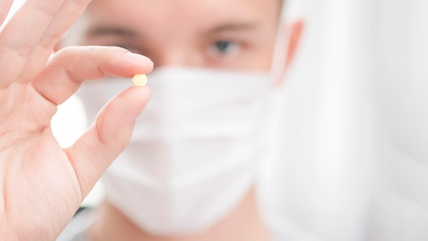 Man in protection mask holding a pill in his hands Copy space