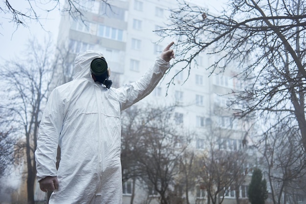 Man in protective clothing pointing up environmental disaster