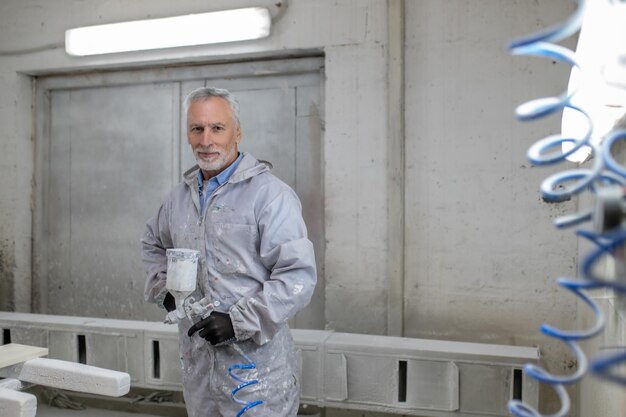 Foto uomo in abbigliamento protettivo che lavora in un laboratorio di falegnameria