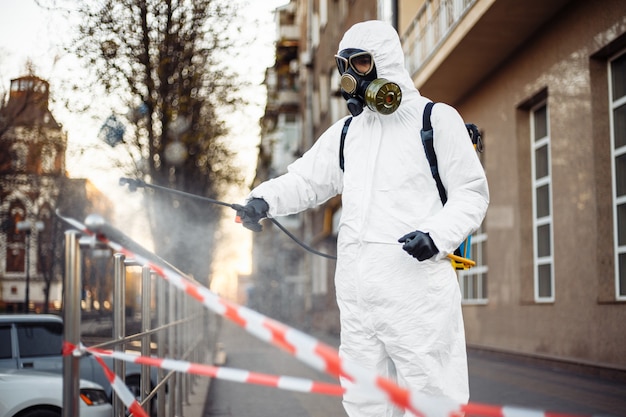 Uomo in equipaggiamento protettivo che disinfetta la città