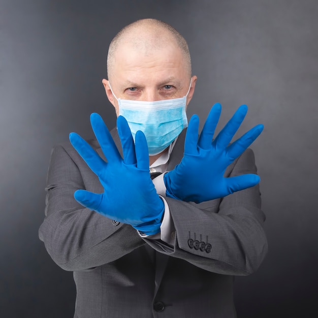 보호 장갑을 입은 남자는 의료용 얼굴 마스크를 보여줍니다. 인간을위한 코로나 바이러스 전염병 및 개인 보호