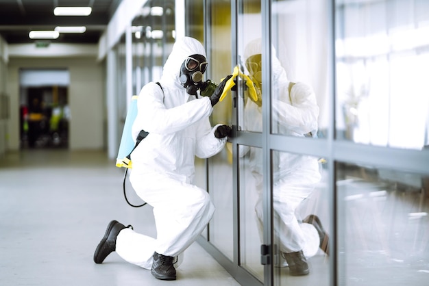 Man in protective hazmat suit washes office furniture to preventing the spread of coronavirus