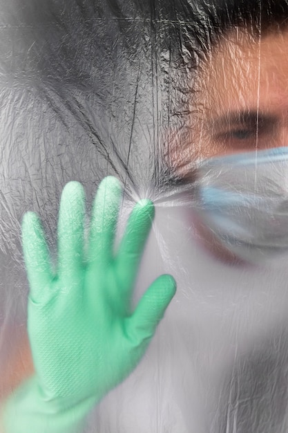 Man in protective mask and gloves self-isolated in his apartment during coronavirus infection