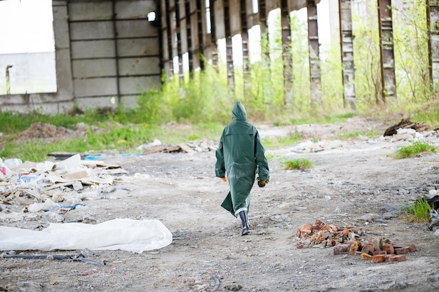 A man in a protective mask and protective clothing explores the\
danger zone ecological catastrophe selective focus