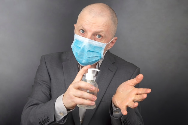 L'uomo in una maschera medica protettiva durante la quarantena disinfetta le mani