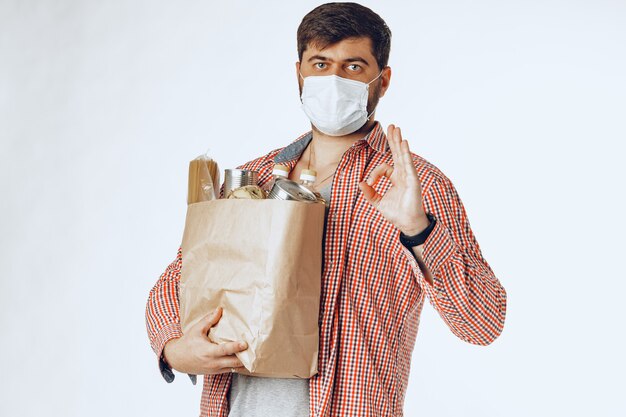 Man in a protective medical mask with a bag from a grocery store. Food delivery