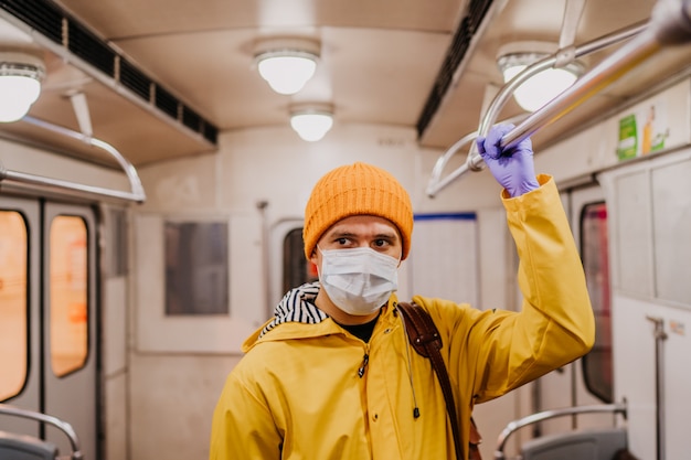 Человек в защитной медицинской маске и жёлтой куртке в одиночестве в вагоне метро думает о том, как избежать cvid-19. Концепция здравоохранения