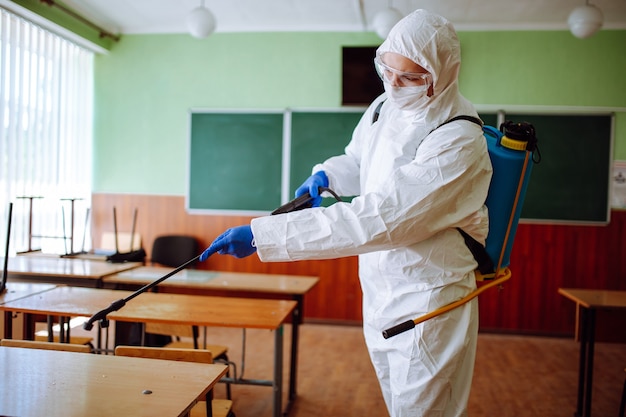 Man in a protective suit disinfecting a classroom