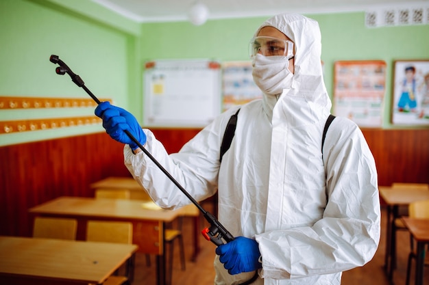 Man in a protective suit disinfecting a classroom