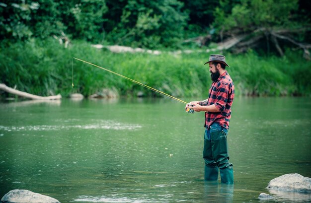 Photo man pulling fishing rod fisherman man on river or lake with fishing rod